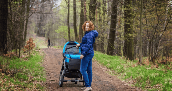 žena s kočárkem na lesní cestě